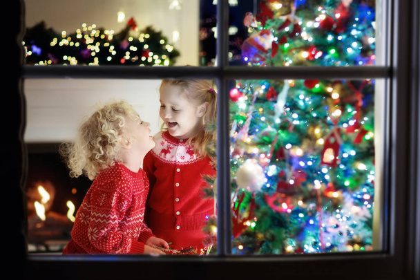 A gyerekek a karácsonyfa. Gyerekek a kandalló karácsony estéjén - Fotó, kép