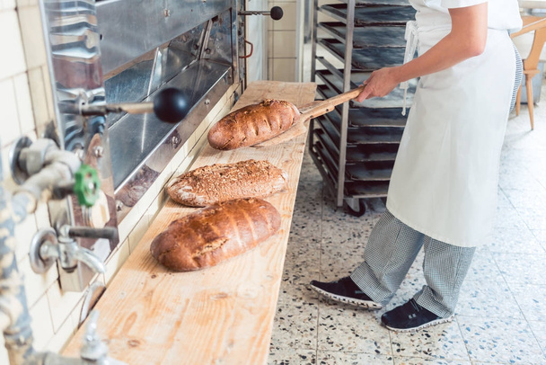Vrouw in bakkerij brood aan boord brengen - Foto, afbeelding
