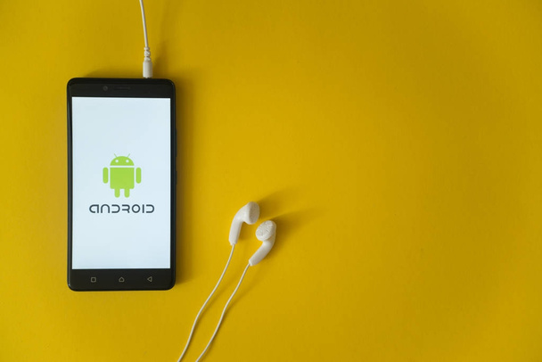 Android logo on smartphone screen on yellow background - Foto, imagen