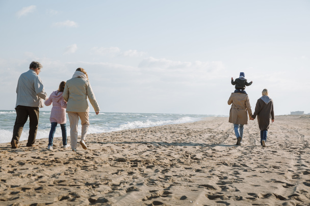 famiglia multigenerazionale a piedi sulla riva del mare
 - Foto, immagini