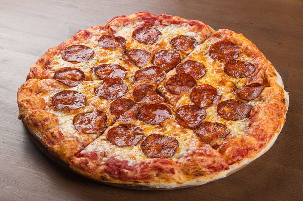 in Stücke geschnitten Pizza Wurst, Salami und Käse auf einer hölzernen Platte - Foto, Bild