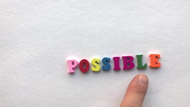 Imposible. letras de madera coloreadas sobre una hoja de papel blanca
 - Imágenes, Vídeo