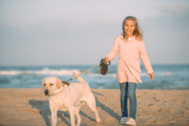 kid walking with dog at seaside - Photo, Image