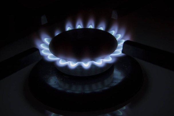 Płonący kuchenka gazowa płyta grzejna niebieskie płomienie zbliżenie w ciemności na blac - Zdjęcie, obraz