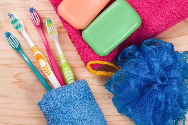 Kartáčky na zuby, mýdlo, houba, ručník na dřevěný stůl. hygienické výrobky. Pohled shora - Fotografie, Obrázek