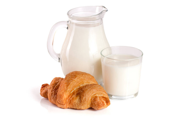 Kruik en glas melk met croissant geïsoleerd op witte achtergrond - Foto, afbeelding