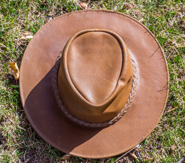 Hnědý klobouk kovbojský spočívá na čerstvé trávě za slunečného počasí - Fotografie, Obrázek