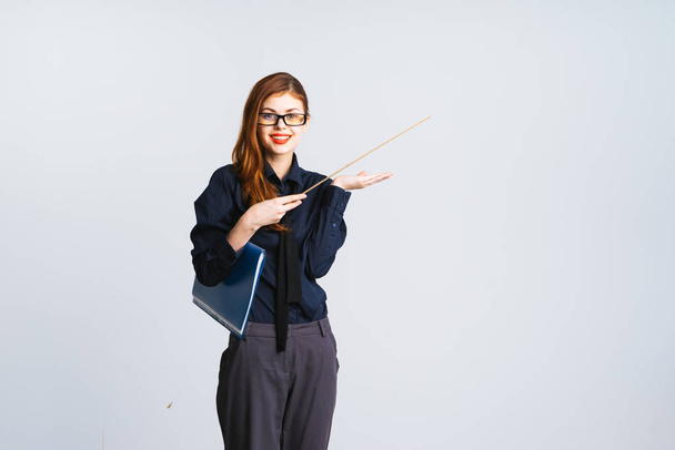 young stylish girl in office clothes smiling and holding a pointer and a folder with papers in her hands - Foto, Imagen