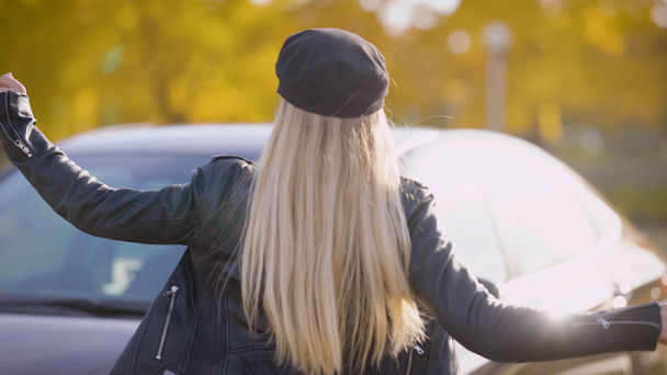 Une femme mignonne et joyeuse avec une casquette sur la tête rit et sourit, la dame est debout à côté de la voiture, dans sa main les clés
 - Séquence, vidéo