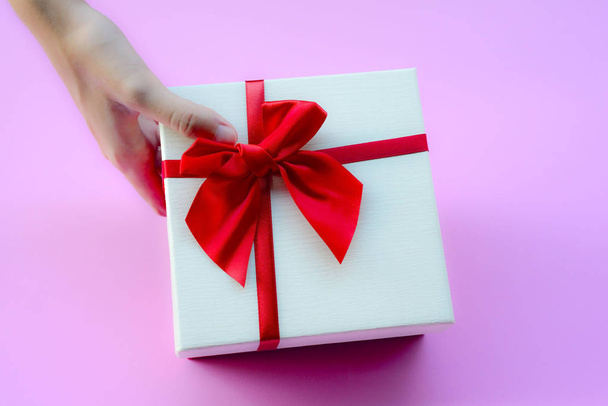 Holiday and surprise concept. Female hands hold boxes wrapped in white and pink paper with red  bows - Photo, Image