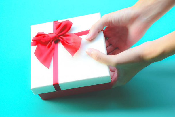 Holiday and surprise concept. Female hands hold boxes wrapped in white and pink paper with red  bows - Foto, immagini