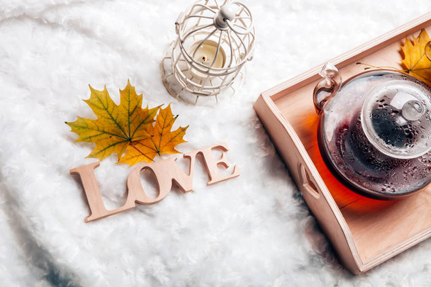 autumn home scene, Scandinavian style. A warm knitted sweater, candles, a cup of warm tea and other decor on a tray in bed. Lazy cold weekend.Love - Foto, Imagem