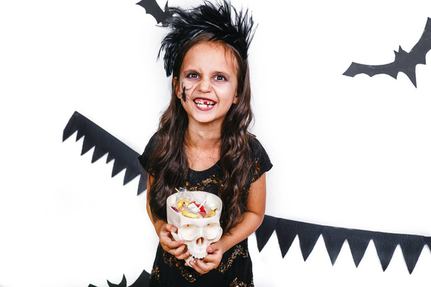 Happy girl in a halloween costume holding skull and having fun - Фото, изображение