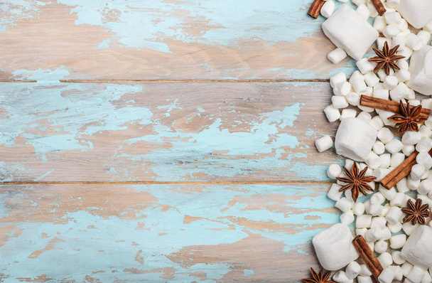 weiße Marshmallows und winterliche Gewürze auf blauem Holzgrund - Foto, Bild