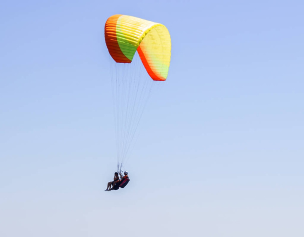 Αθλητικός τύπος πετάει το αλεξίπτωτο στον ουρανό. Αλεξίπτωτο πλαγιάς αθλητισμού επικίνδυνα - Φωτογραφία, εικόνα