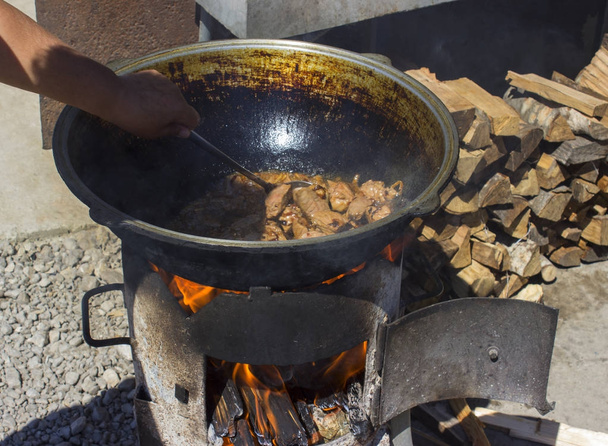 Sartén de hierro fundido para la cocina tradicional de Rusia, se encuentra junto a la madera. ver el fuego
 - Foto, imagen