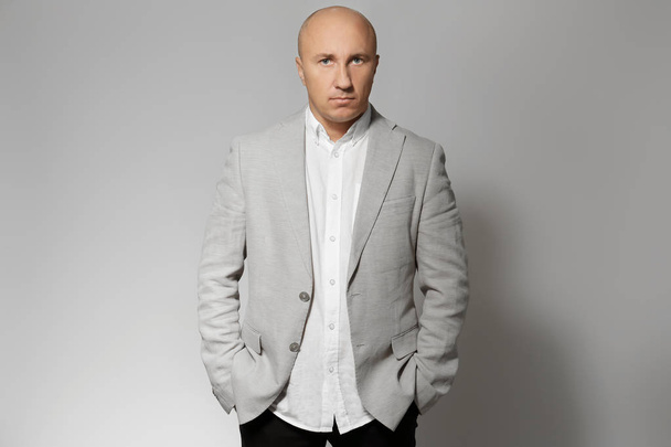 Bald man in jacket on grey background - Foto, immagini