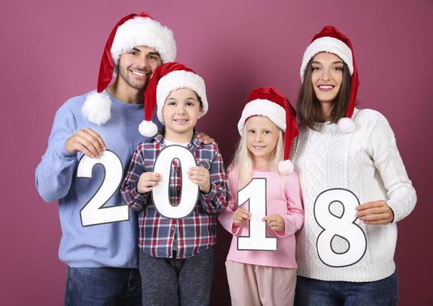 Happy family with paper figures 2018 on color background. Christmas celebration concept - Foto, Imagen