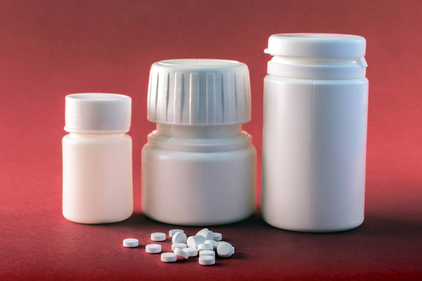 赤の背景に分離されたさまざまな種類の白い錠剤と白い錠剤ボート - 写真・画像