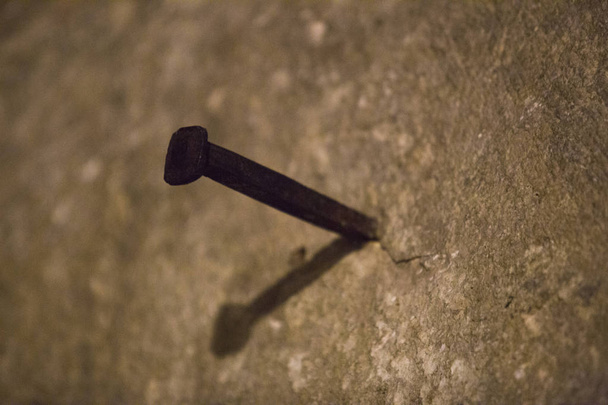 in a light brown wall a large, rusty nail  - Photo, Image