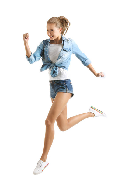 Young beautiful woman running against white background - Valokuva, kuva