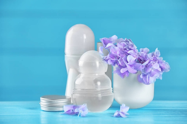 Desodorantes para mujeres y flores en la mesa
 - Foto, Imagen