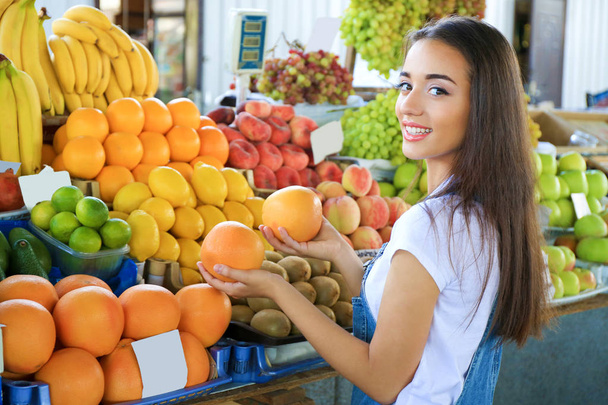 Young woman choosing fruits at market - Foto, Bild