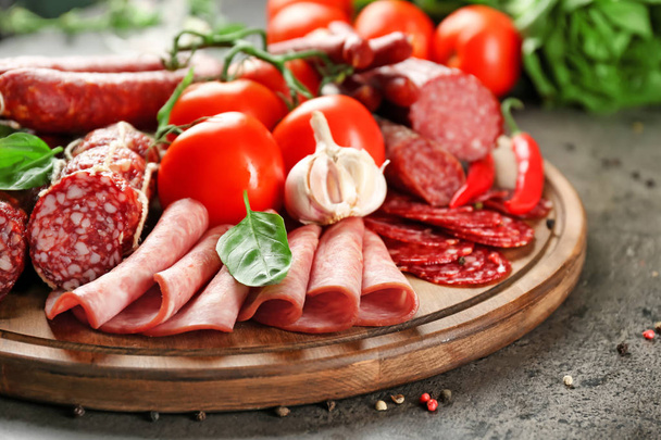 Delicious sliced sausages with vegetables on wooden board - Foto, Bild