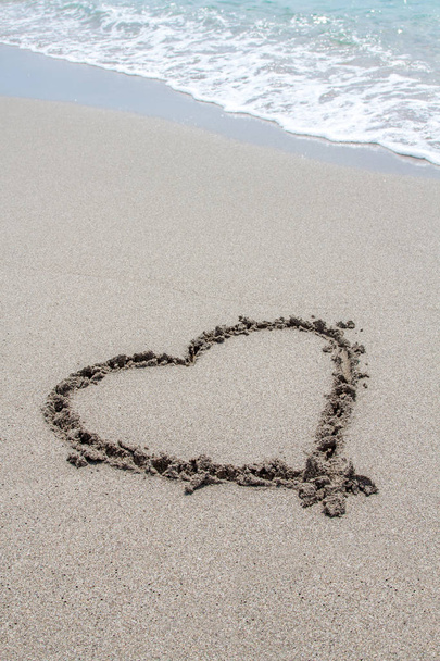 Heart drawn on the beach sand with sea foam and wave, angled - Zdjęcie, obraz