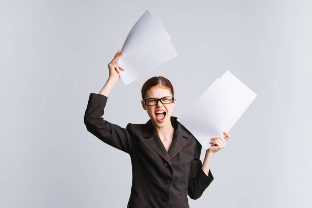 uma jovem garota de sucesso em óculos e um terno rigoroso grita e mantém documentos
 - Foto, Imagem