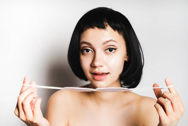 young beautiful girl with black short hair smiles and holds something white - Photo, image