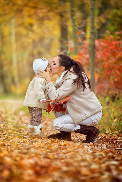Anya megcsókolja a kis lánya a kifolyó, őszi park. - Fotó, kép