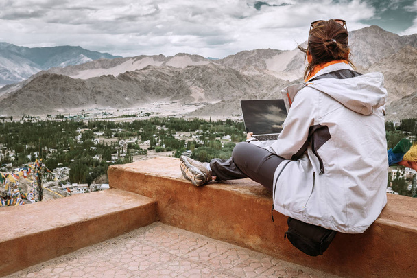 Traveler with laptop sits on top view point on the mountain valley - Foto, imagen
