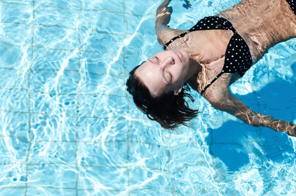 Mulher flutuando na piscina
 - Foto, Imagem