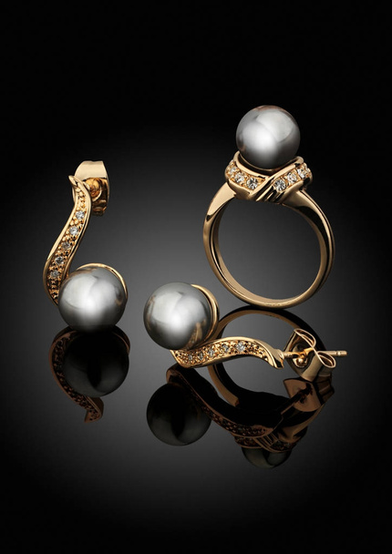 Golden jewelry set with pearls on black background with reflecti - Foto, afbeelding