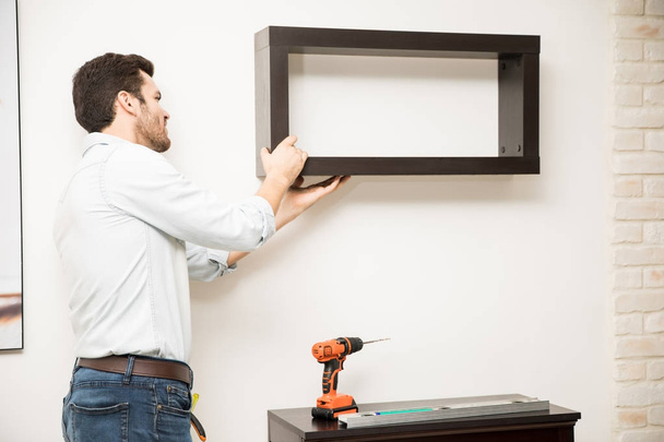 Man installing a shelf at home - Фото, зображення