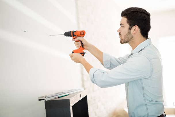 Man using power drill on a wall - Фото, зображення