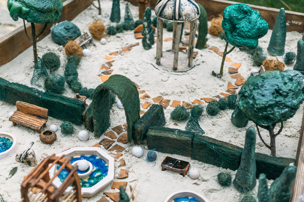 Miniature houses, toy landscape objects in sandbox. Anti-stress and soothing sand therapy. - Photo, Image