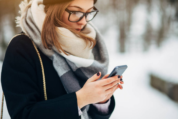 Girl in winter park using smartphone - Foto, immagini