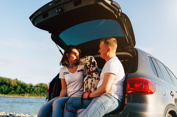 Couple and dog sitting in car trunk - 写真・画像