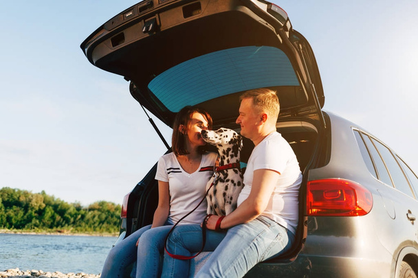 Couple and dog sitting in car trunk - Foto, Imagen