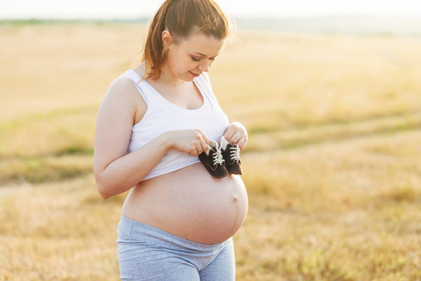 terhes nő babacipővel - Fotó, kép