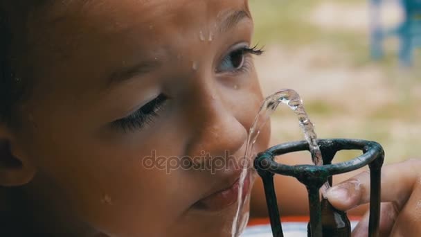 Boldog kis fiú vicces ivóvíz egy ivókút, a játszótéren, a lassú mozgás - Felvétel, videó