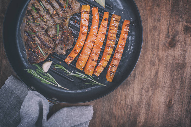  кусок говядины на круглой сковороде с жареной морковью
 - Фото, изображение