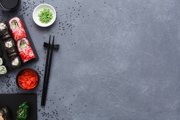 Conjunto de vista superior de sushi maki y rollos sobre fondo rústico gris y sésamo
 - Foto, Imagen