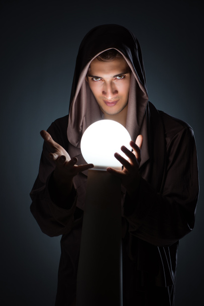 Junger Zauberer mit Kristallkugel im dunklen Raum - Foto, Bild