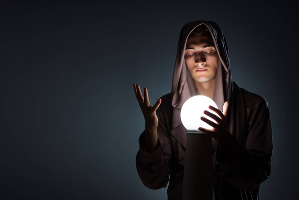 Young wizard with crystal ball in dark room - Valokuva, kuva