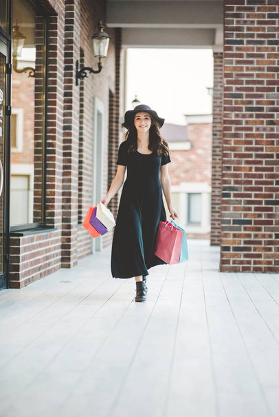 Fiatal nő bevásárlószatyrokkal kisétál a boltból - Fotó, kép