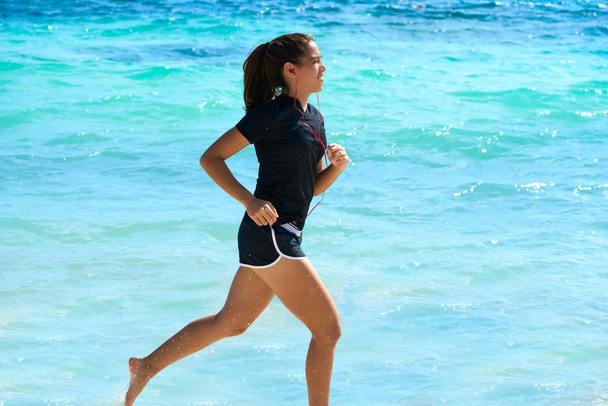 Latin girl running in caribbean shore beach - Фото, изображение