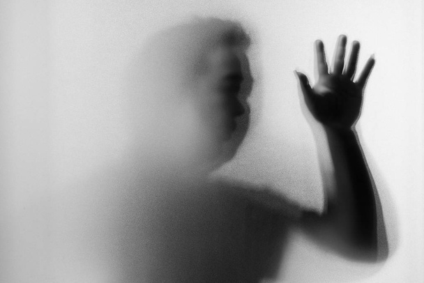 Теневая размытость человека ужасающего за замерзшим стеклом
 - Фото, изображение